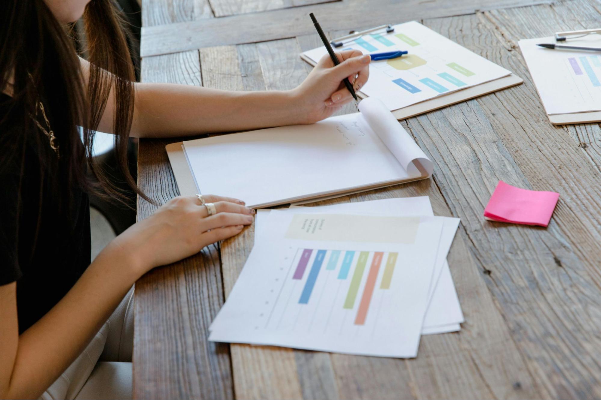 A girl starts to write at a blank paper on wooden desk